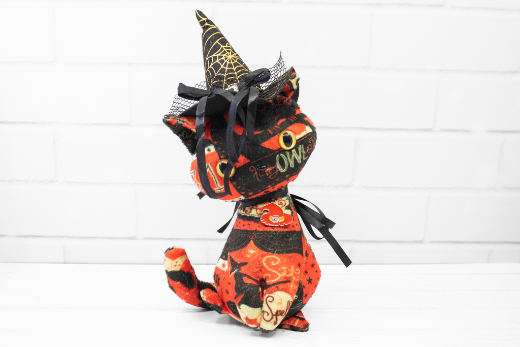 Halloween-themed cat plush toy with a witch hat on a white background