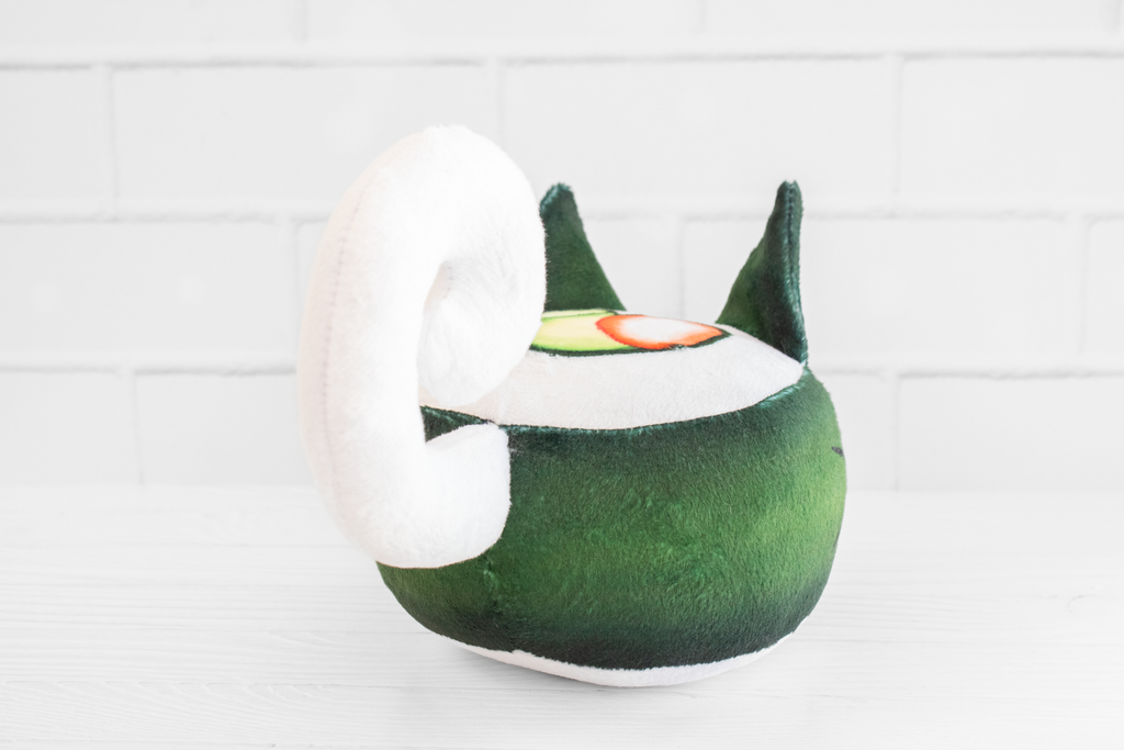 A handmade green plushie cat in the shape of a sushi roll with green ears and a white tail sticking out. It has a kawaii face with one eye winking and an open pink mouth that shows cat fangs. The top and the bottom have a white base and an image of a california roll's fillings in the shape of a heart. 